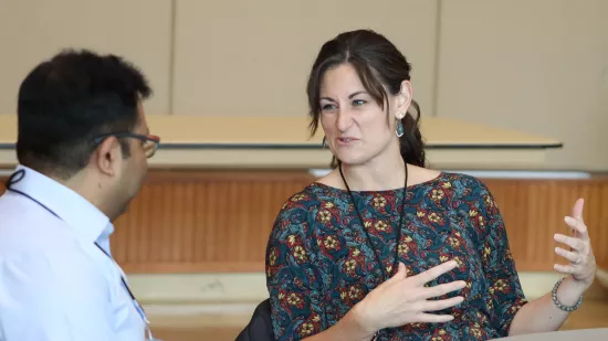 A woman speaks to a man seated at a table.