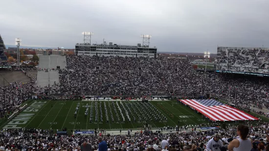 A football stadium with a large American flag on the field.