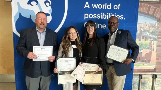 Two men and two women hold certificates while smiling.