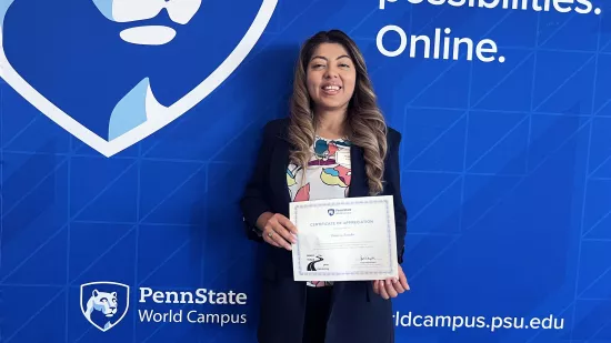A woman holds a certificate against a backdrop of the logo of World Campus.