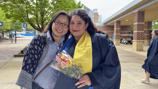 A woman in a graduation gown hugs her boss.