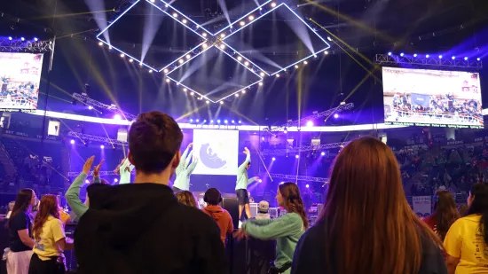 Two people stand in a crowded arena.