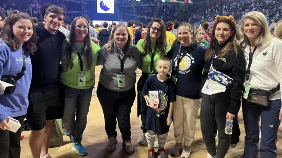 A group of people pose for a photo in a crowded arena.