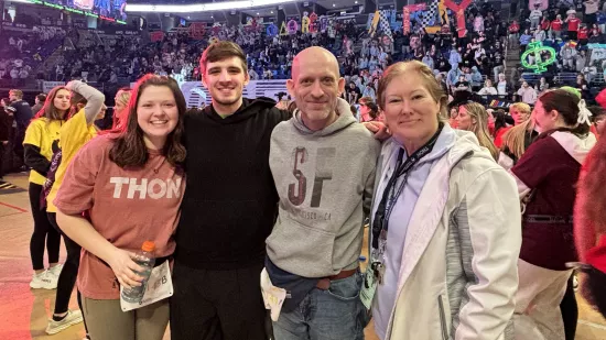 Four people pose in a crowded arena.