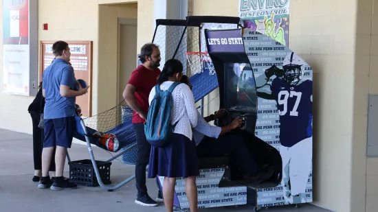 A group of people gather around arcade games.