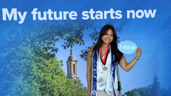 A woman stands in front of a Penn State photo background.
