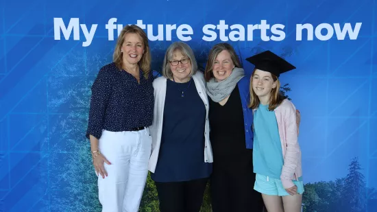 Four women pose in front of a Penn State photo background.