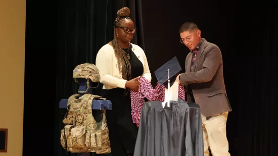 A man and a woman move a collection of red, white, and blue honor cords on a display.