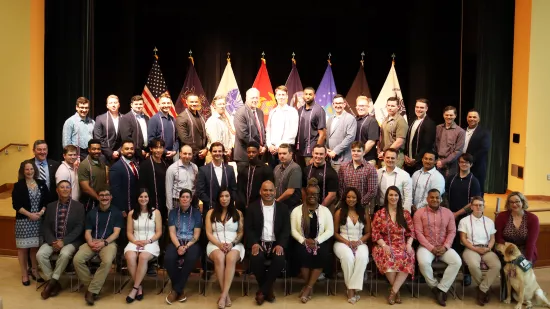 A large group of people pose on a stage for a photo.