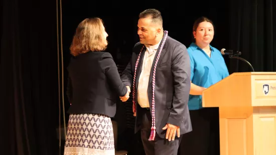 A man shakes a woman's hand on a stage.