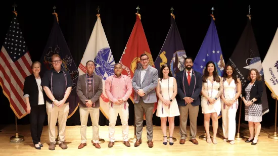 A group of people pose in front of a group of flags.