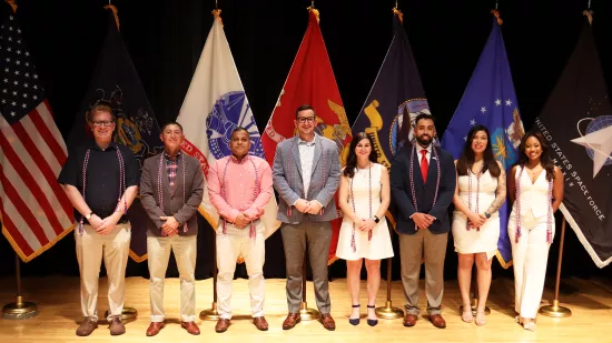 A group of people pose in front of a group of flags.