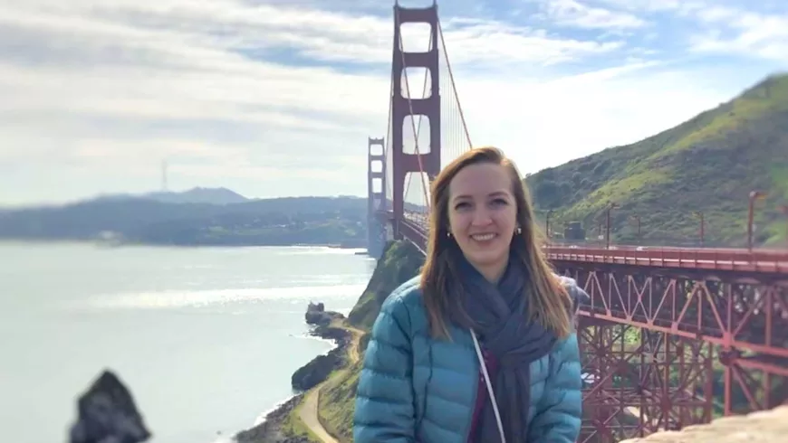 Michelle Hatch sits on a wall with the Golden Gate Bridge in the background