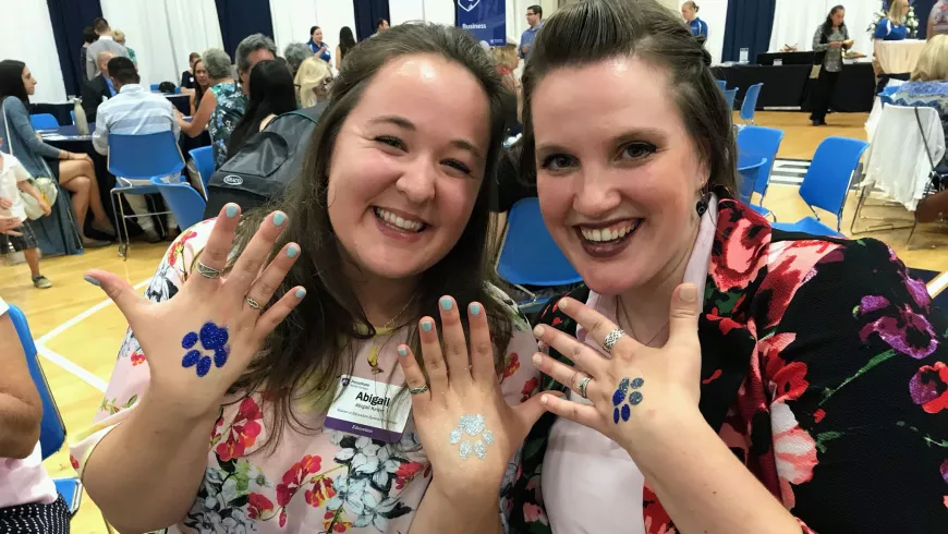 abby keizer and a friend hold up backs of their hands, which have a lion paw print stamped on them