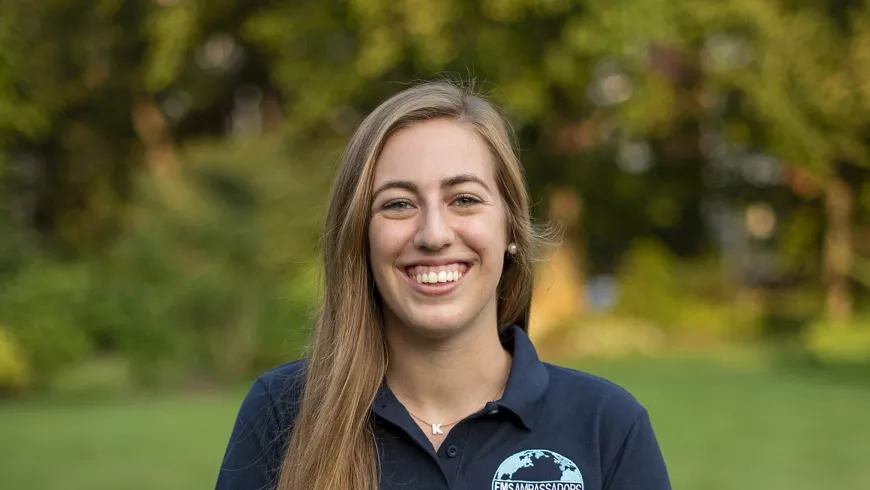 Karen Dedinsky stands in a field wearing a blue shirt