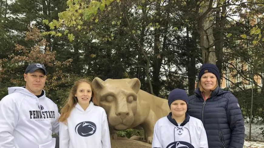 Parents and two kids in Penn State cloths at Lion statue
