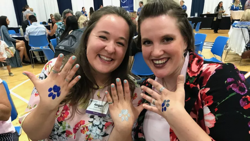 Recent graduates at World Campus Celebration showing off Nittany Lion glitter tattoos