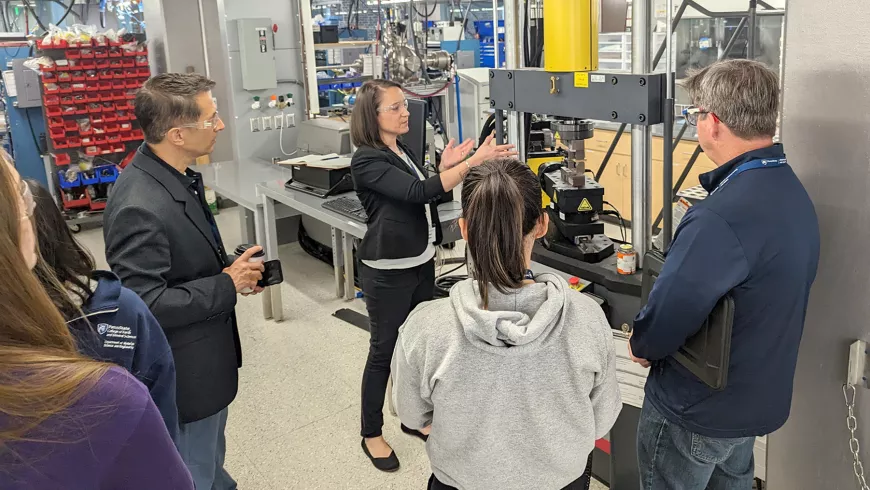 A group of people gather around lab machinery.