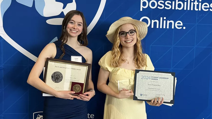 Two women holding plaques stand next to each other smiling.