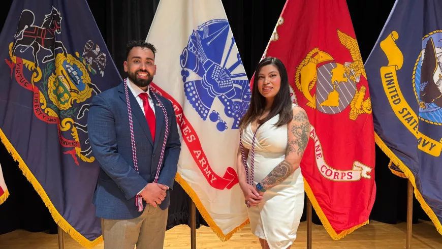 a man and woman stand in front of military flags