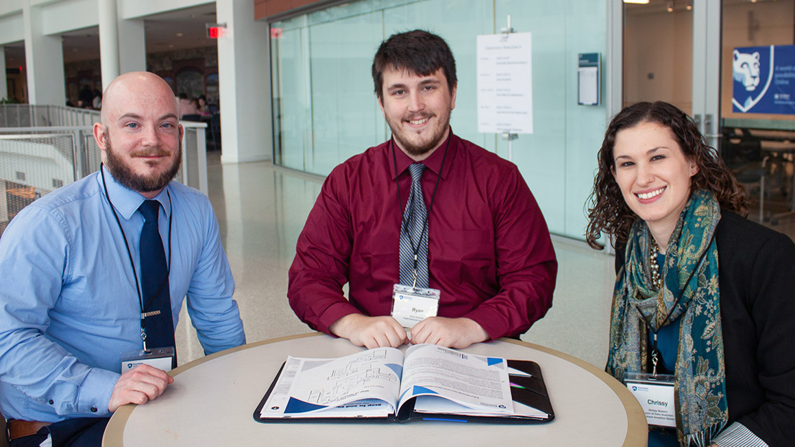 Three Penn State World Campus students are seen at a table after a session at the student leadership conference in 2018.