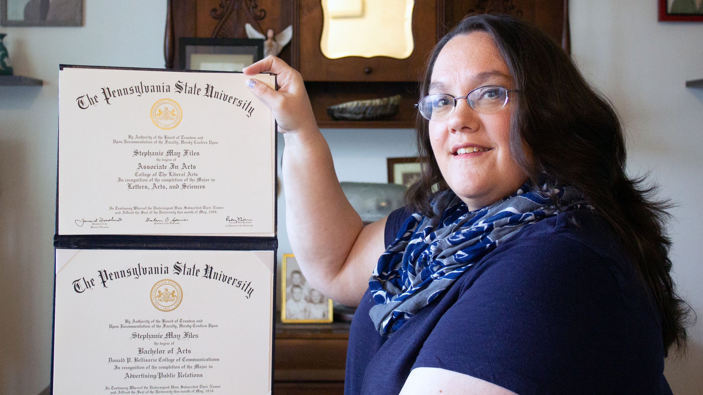 Stephanie Files displays two diplomas in her hands