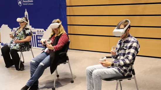 Three people sit while using virtual reality headsets.