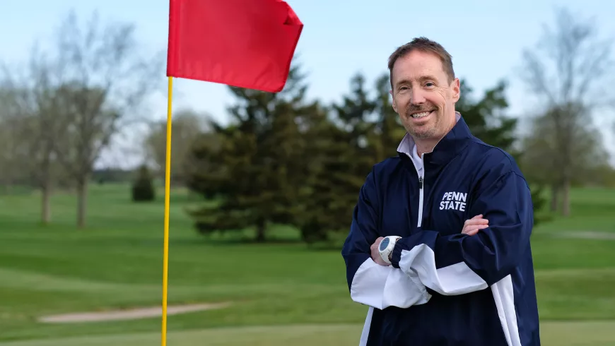 Monty Elam on a golf course, standing next to flag that is in a hole.